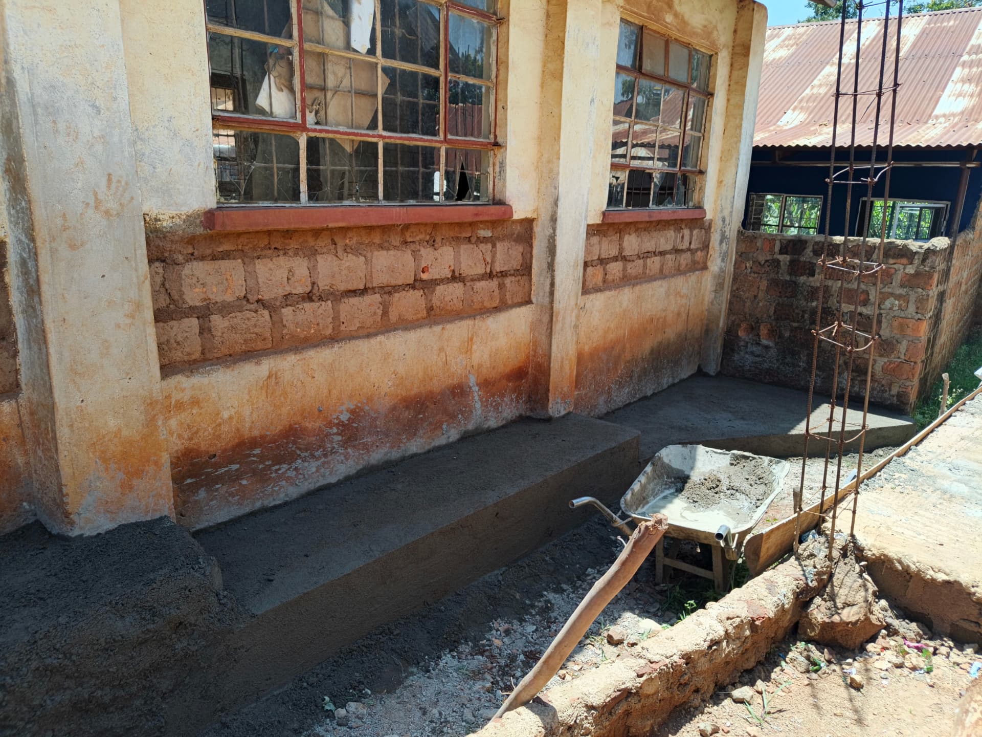 Freshly cast concrete apron and foundation works along the classroom wall