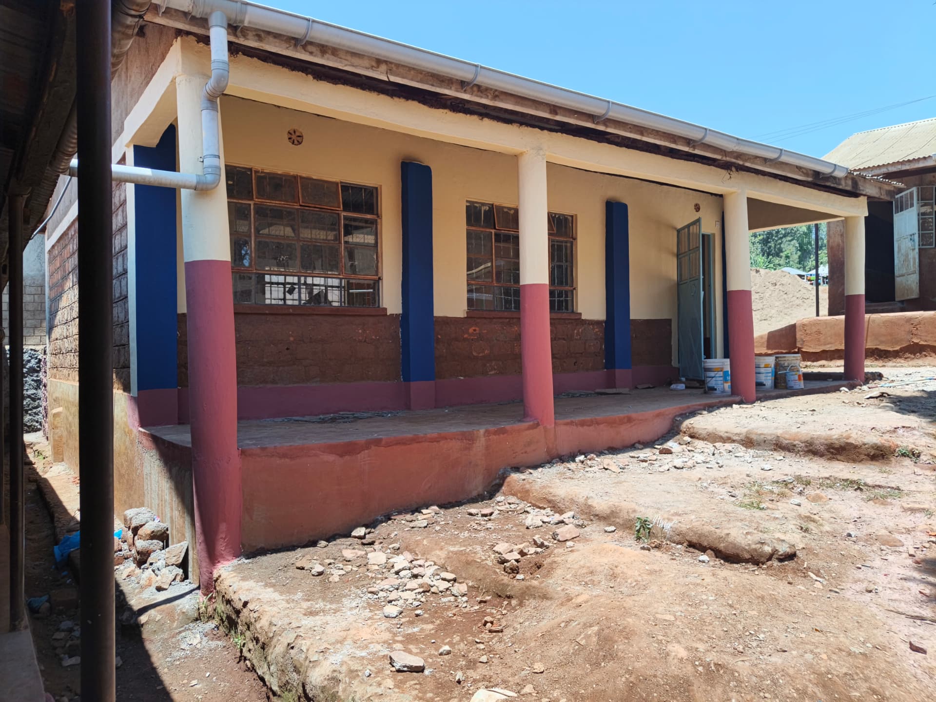 Repainted classroom block with cream walls, blue and maroon pillars