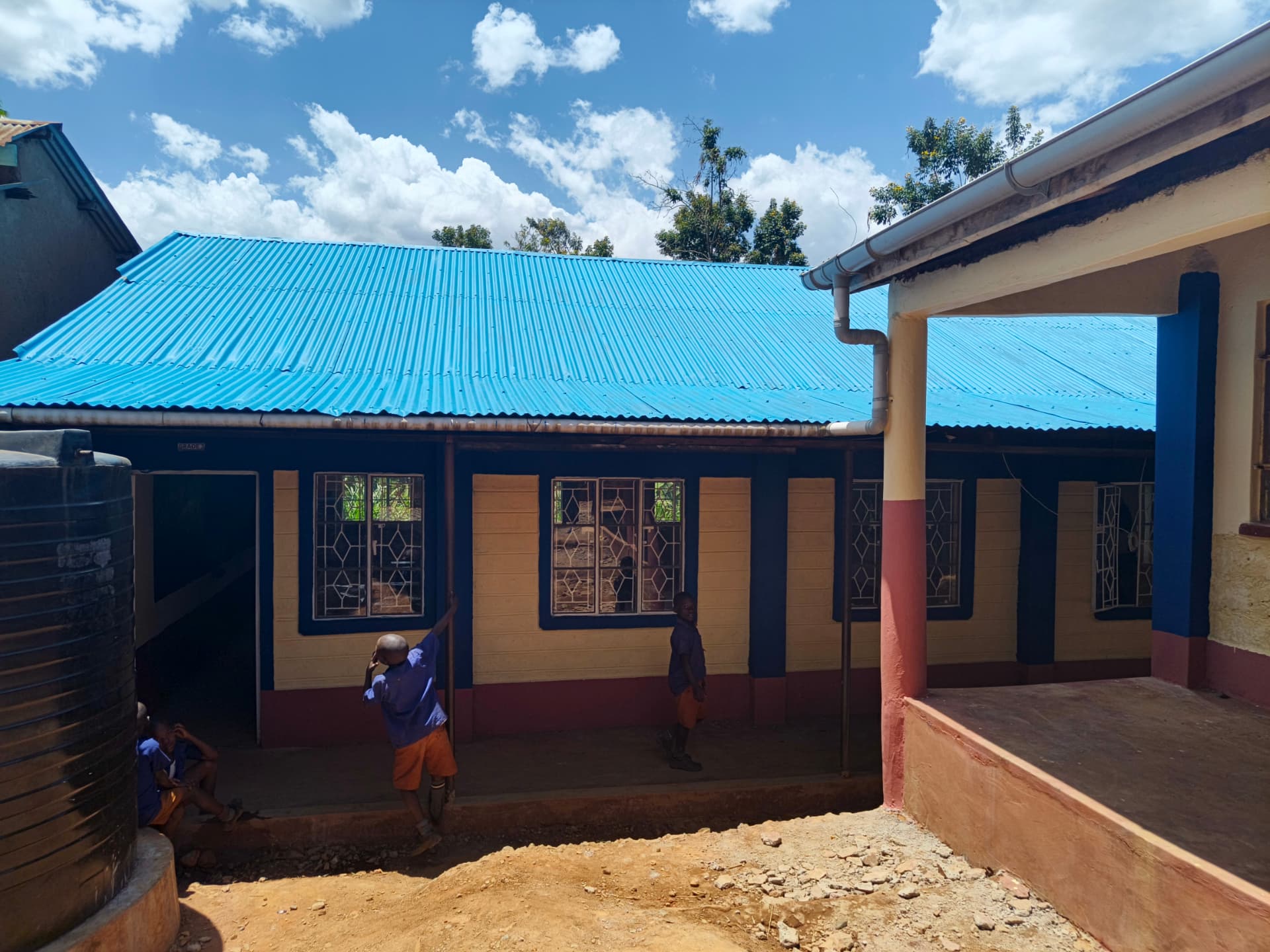 Completed classroom block with blue roof, cream walls and maroon skirting