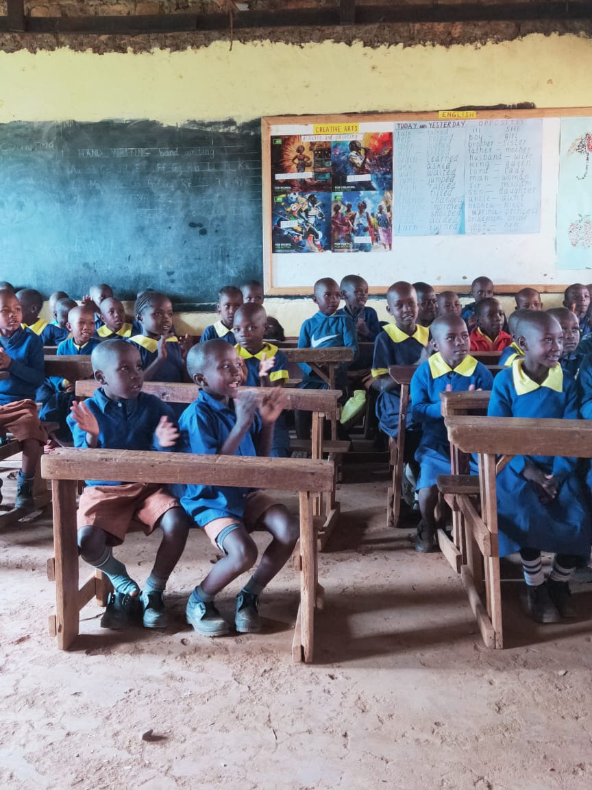 Learners in blue uniforms sharing crowded wooden desks