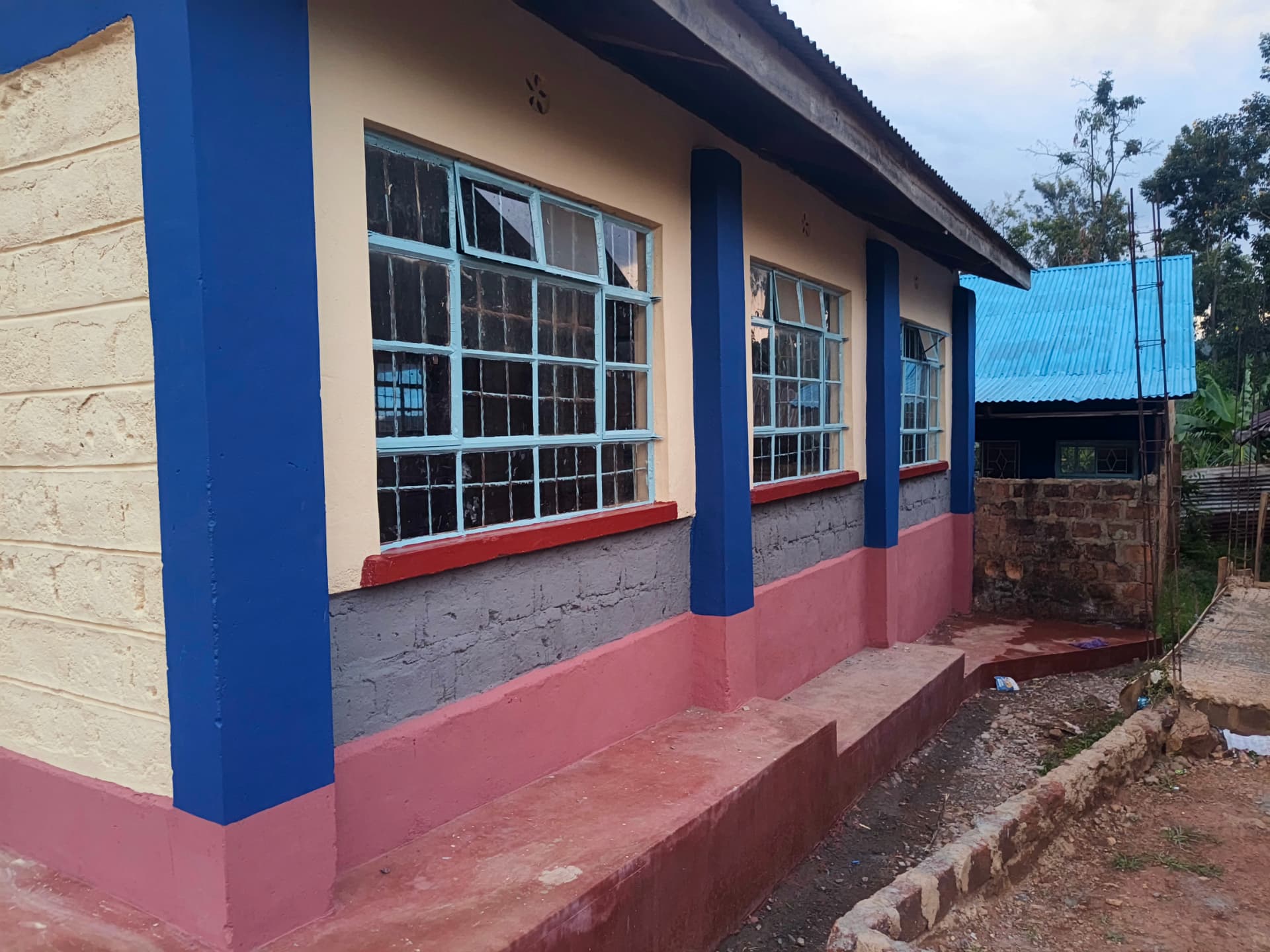 Row of refurbished classroom windows with light blue frames and red sills