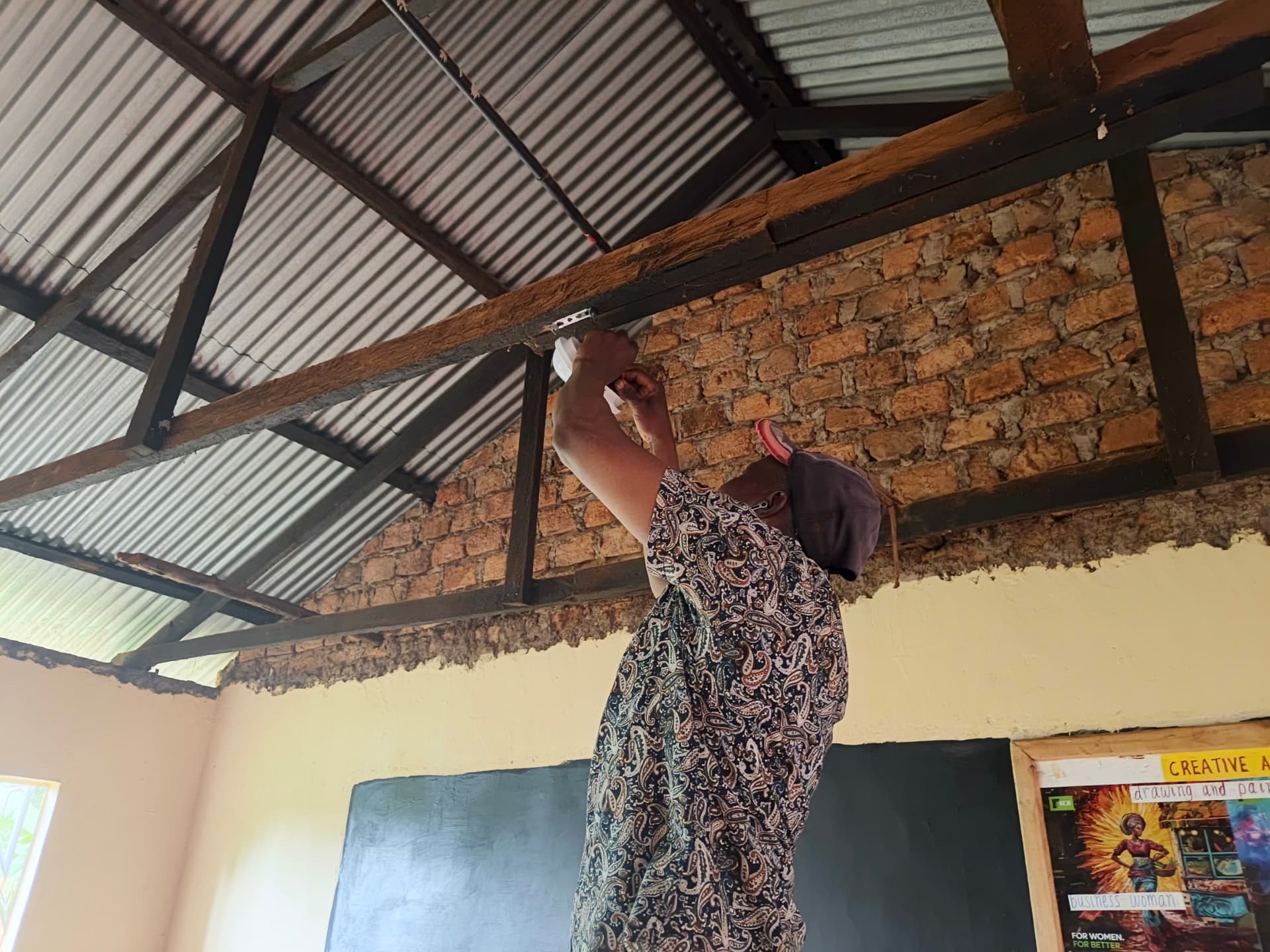 Worker securing a light fitting to the classroom roof truss