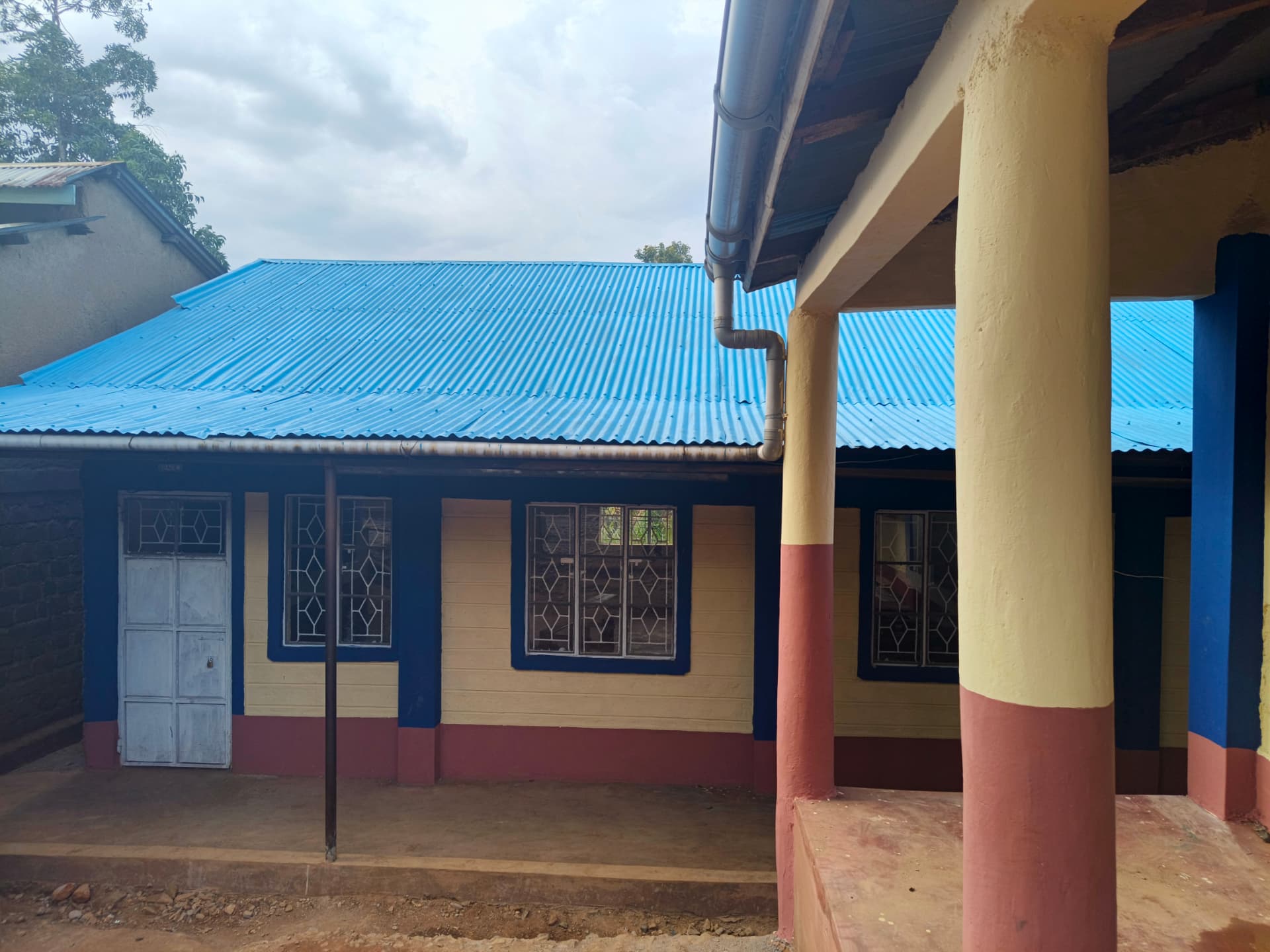 Classroom block with new sky-blue iron roof, cream walls and maroon skirting