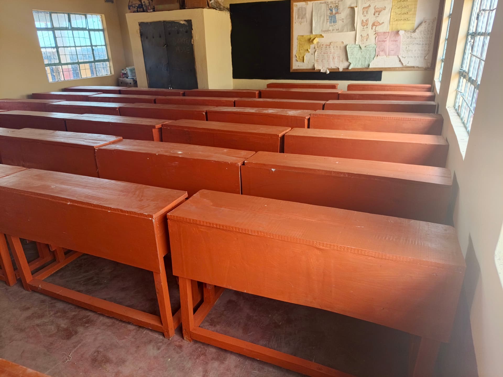 Newly varnished desks and teacher chairs arranged in a freshly painted classroom