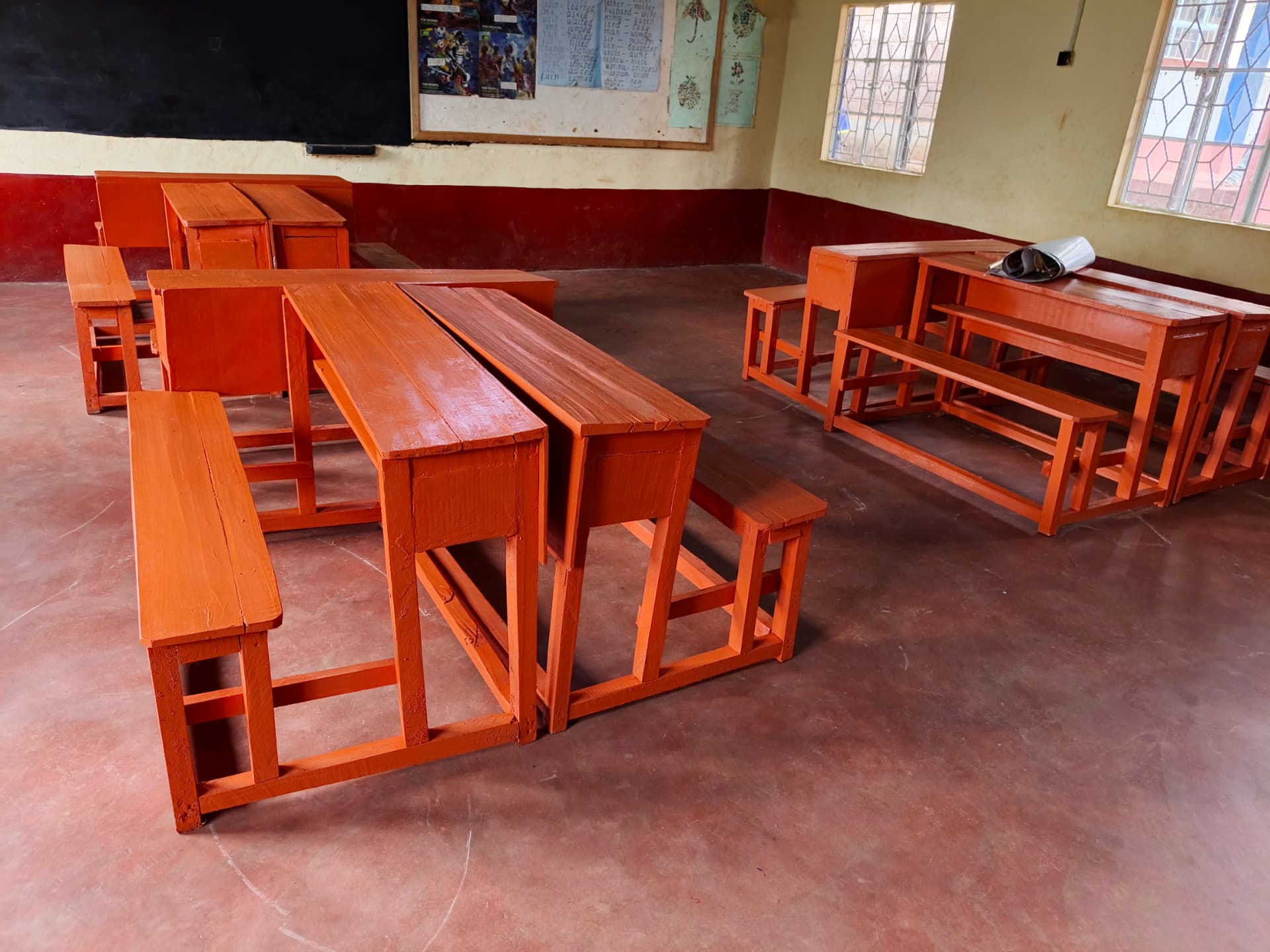 Classroom with rows of varnished wooden desks and benches