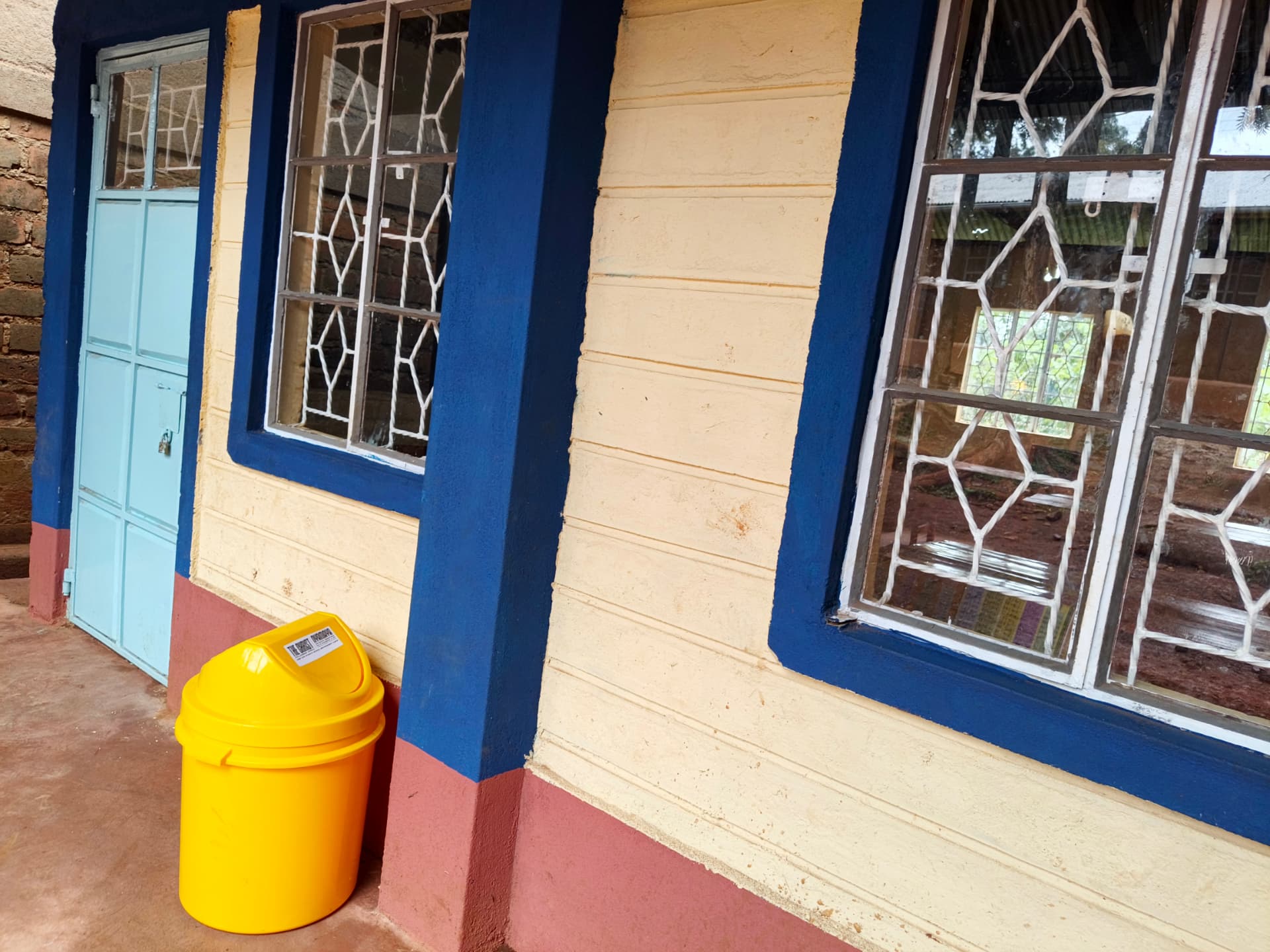 Yellow push-top waste bin placed beside a classroom pillar