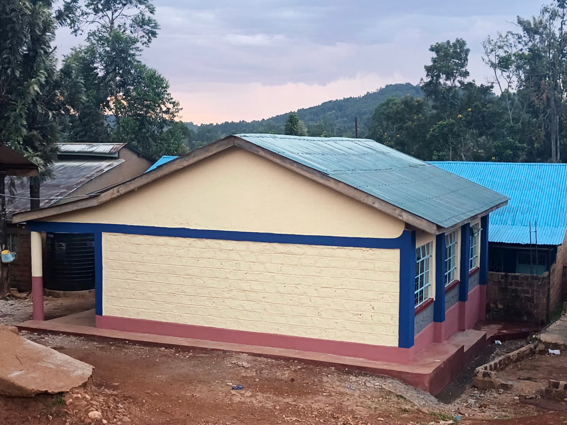 Completed classroom block with cream walls, blue trim and maroon plinth at dusk