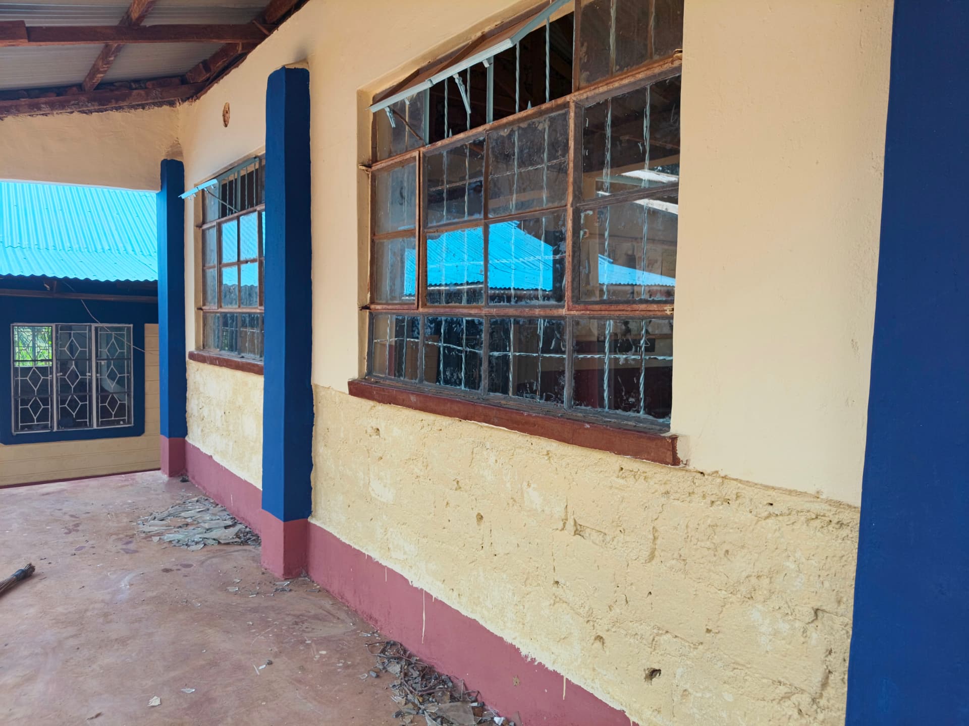 Corridor with old window frames awaiting refurbishment beside repainted pillars