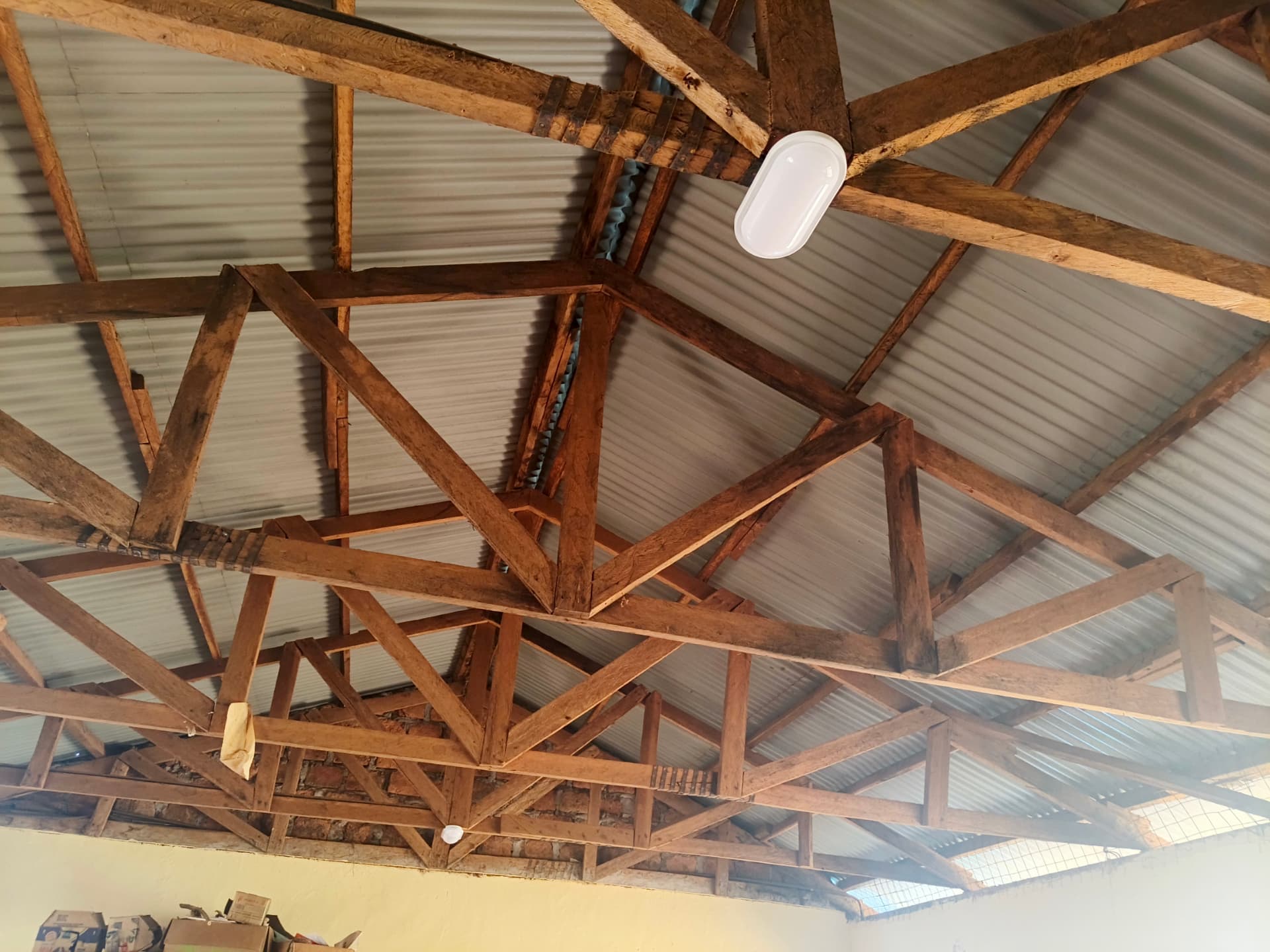 Oval ceiling light fitted among wooden roof trusses