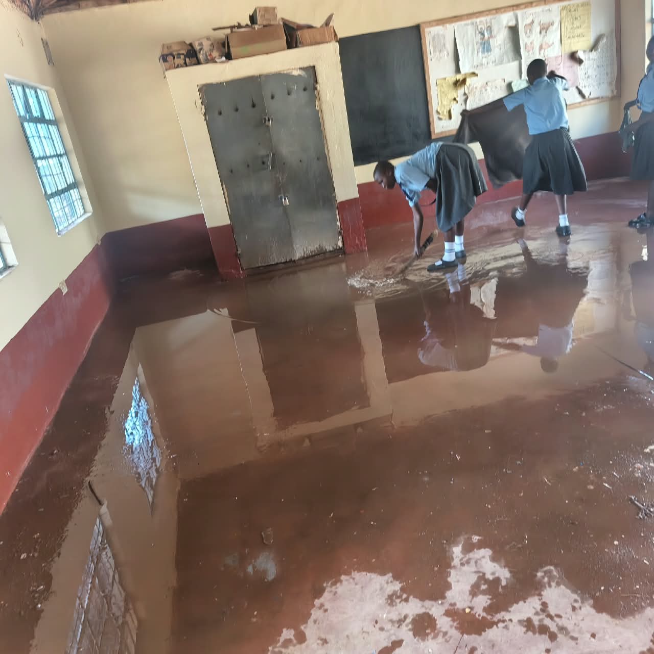 Pupils sweeping a freshly screeded and polished classroom floor
