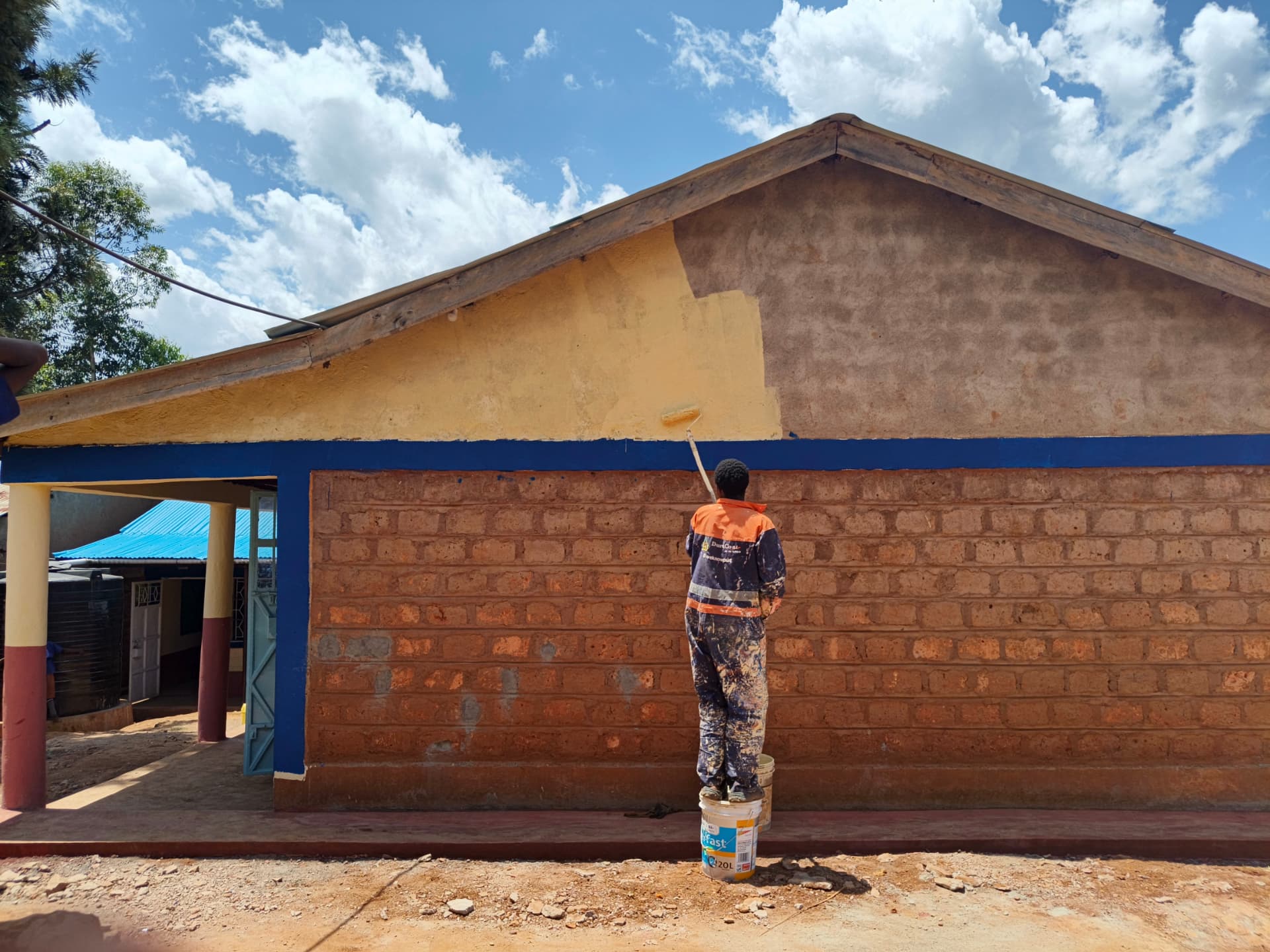 Worker rolling cream paint onto a classroom gable end