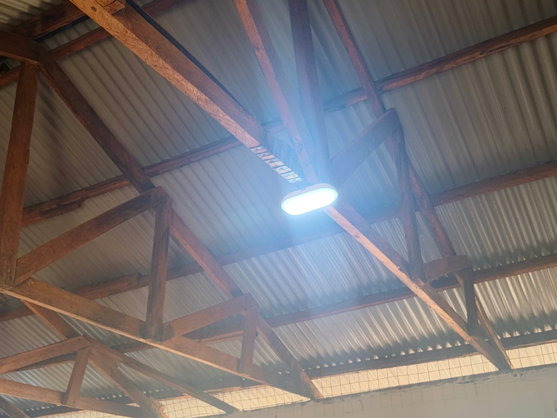 Bright LED ceiling light glowing under the classroom roof trusses