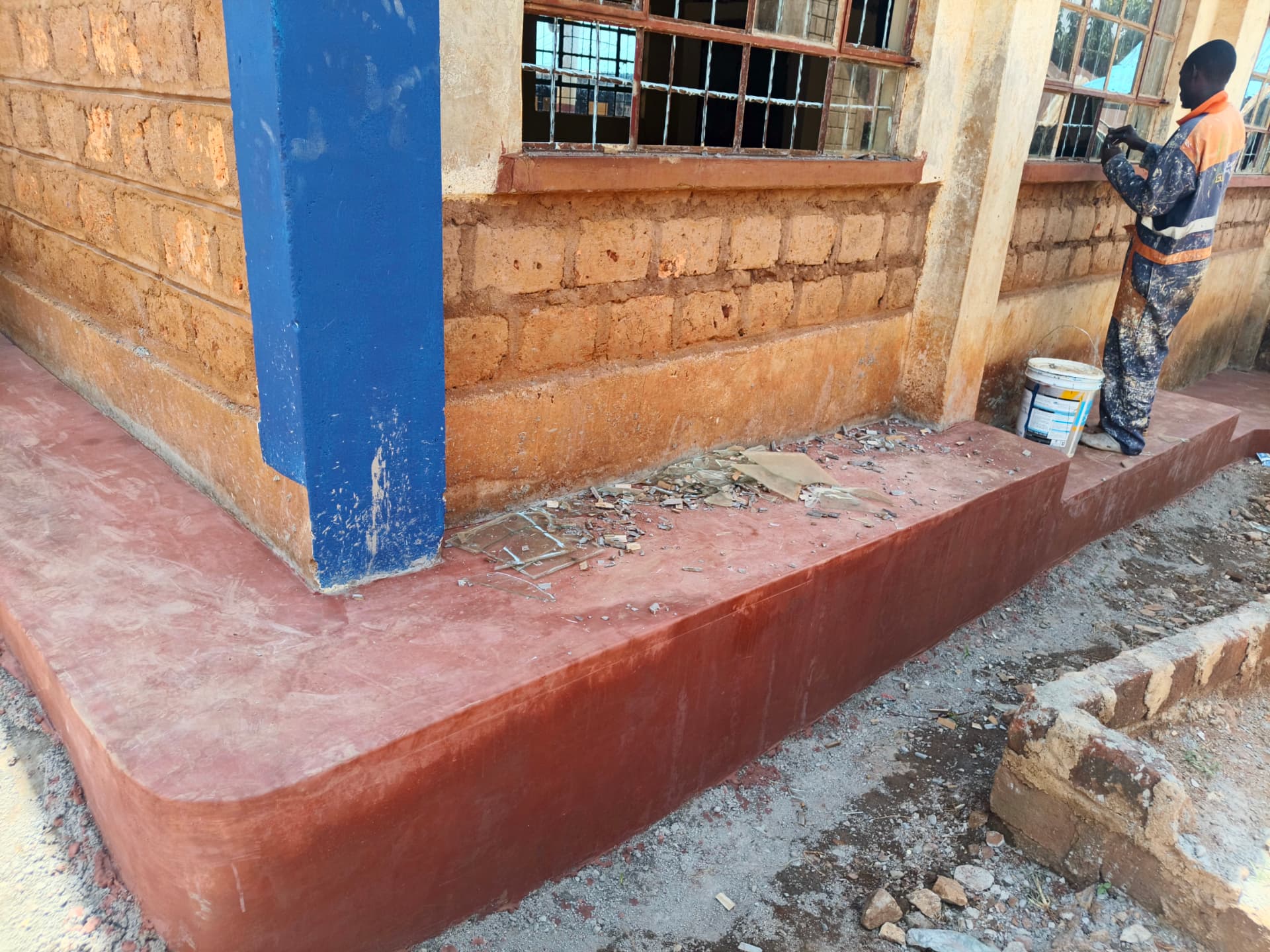 Freshly cast maroon concrete apron along the classroom foundation