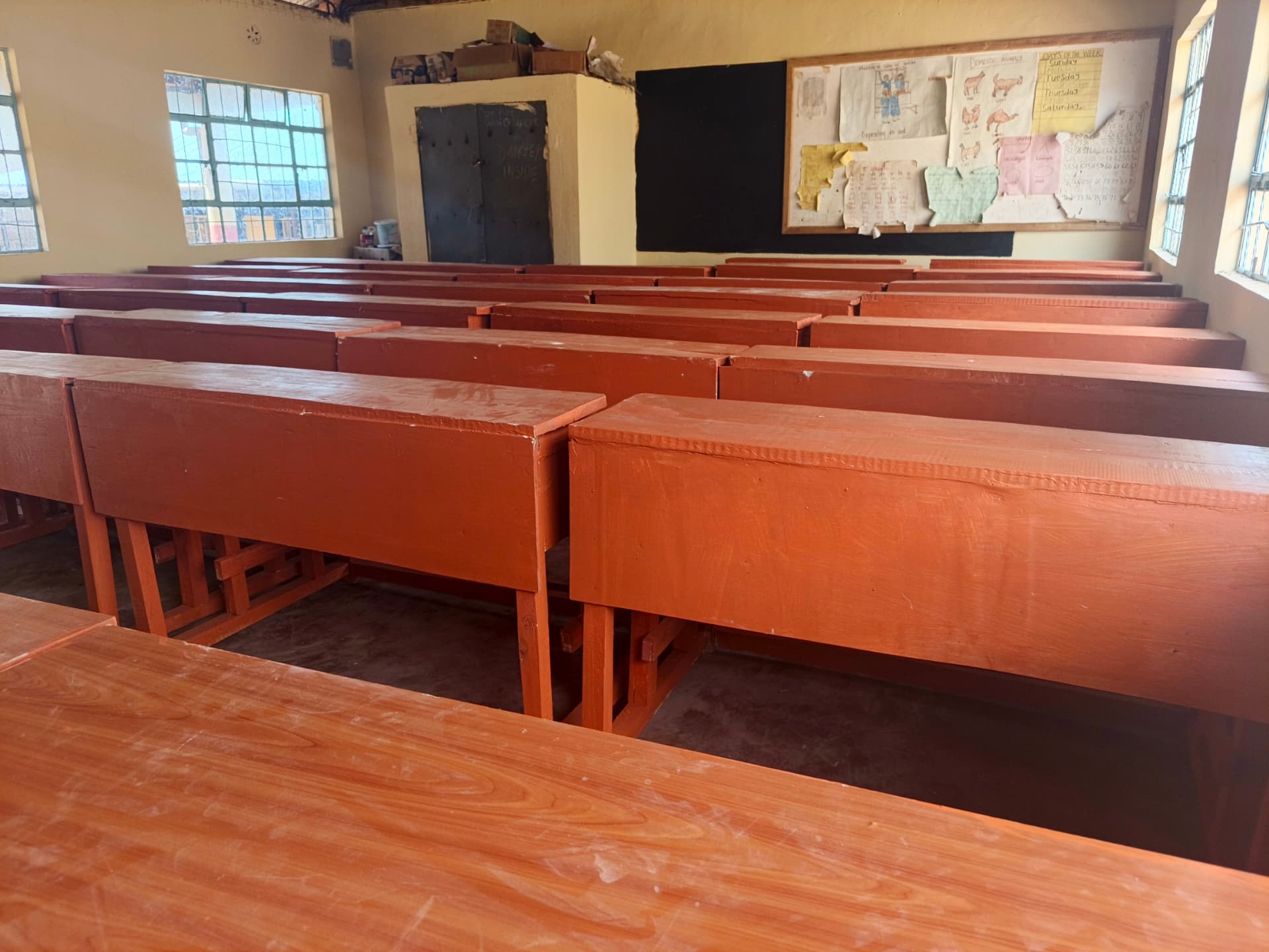 Teacher desks and cushioned chairs beside a blackboard in a finished classroom