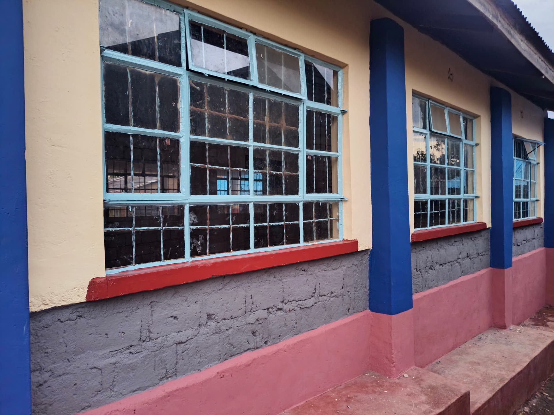 Close view of freshly painted classroom windows and plastered plinth