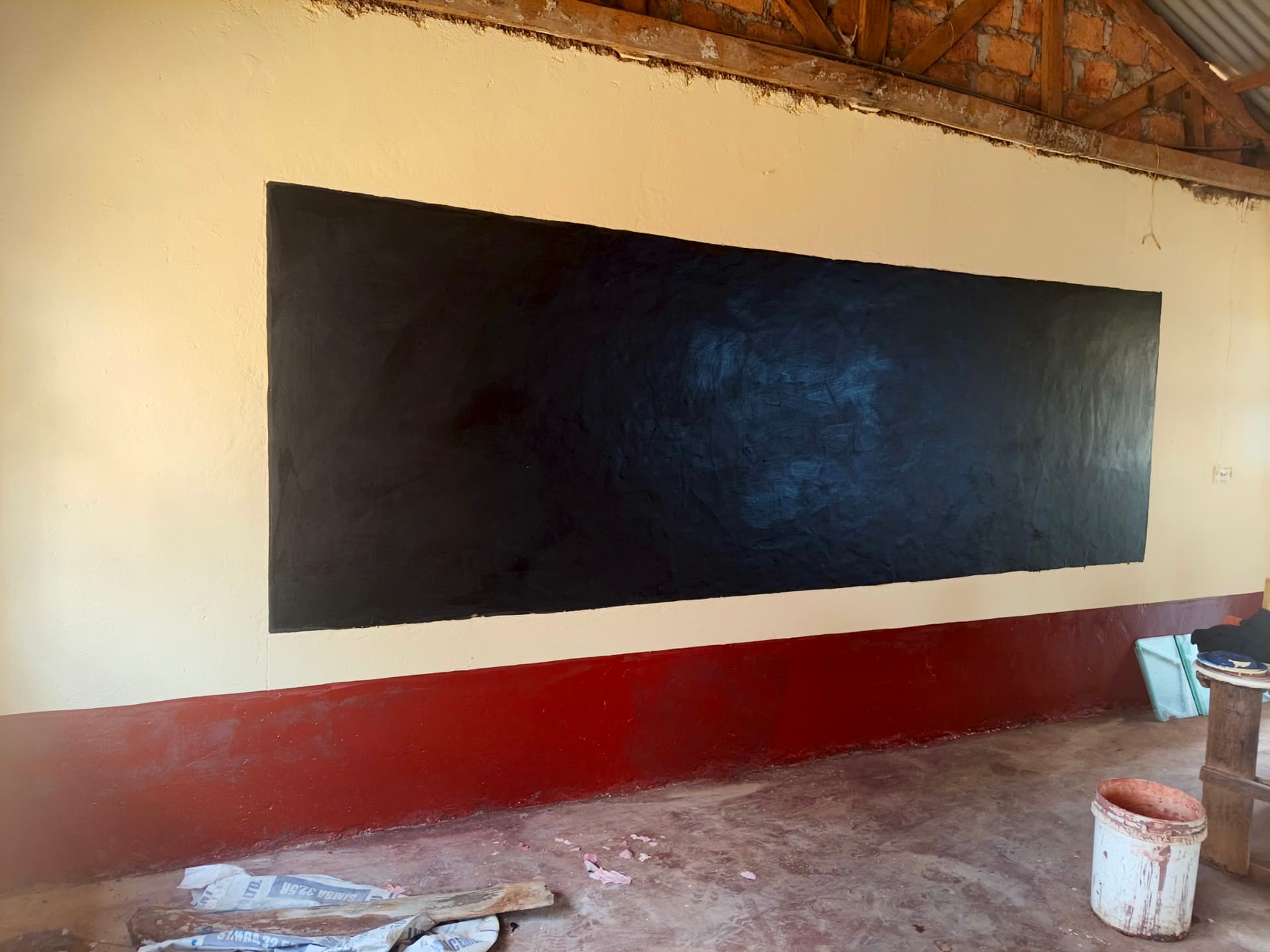Newly finished black chalkboard on a cream classroom wall with red skirting