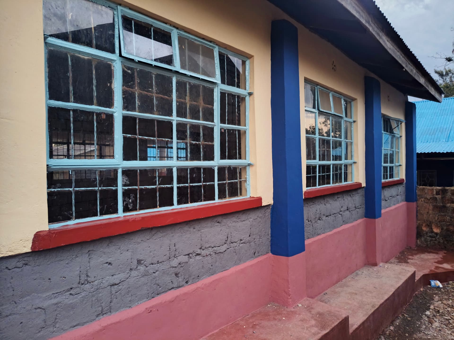Repainted classroom facade with blue pillars and pink plinth