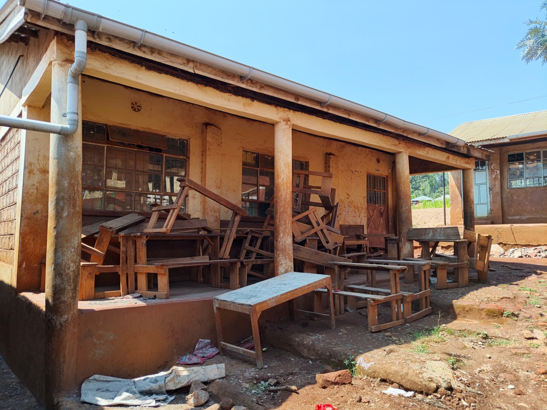 Worn classroom block with broken desks stacked on the veranda