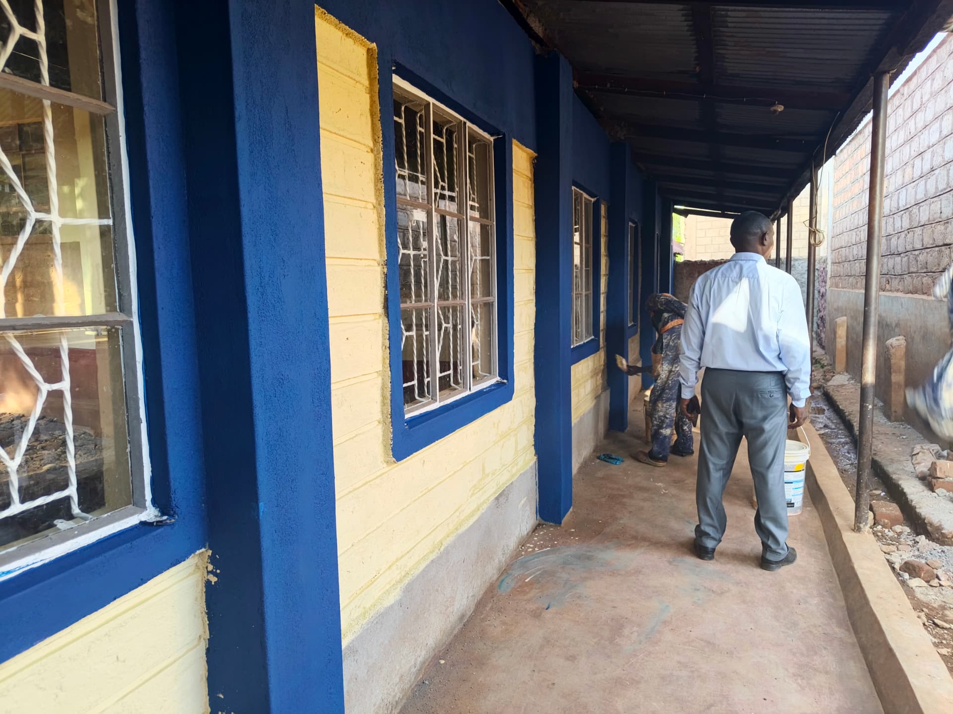 Painted blue and cream classroom corridor with supervisor inspecting