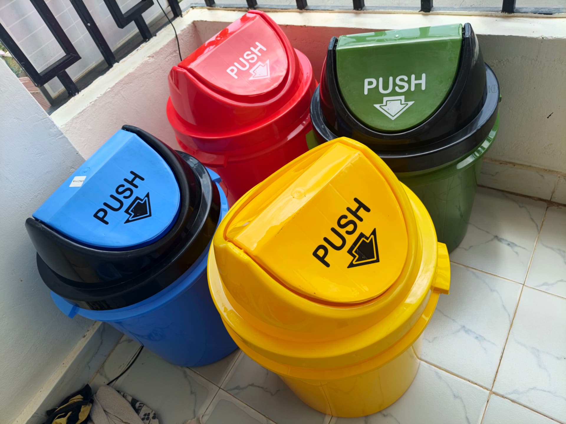 Push-top bins in blue, red, green and yellow lined up on the veranda
