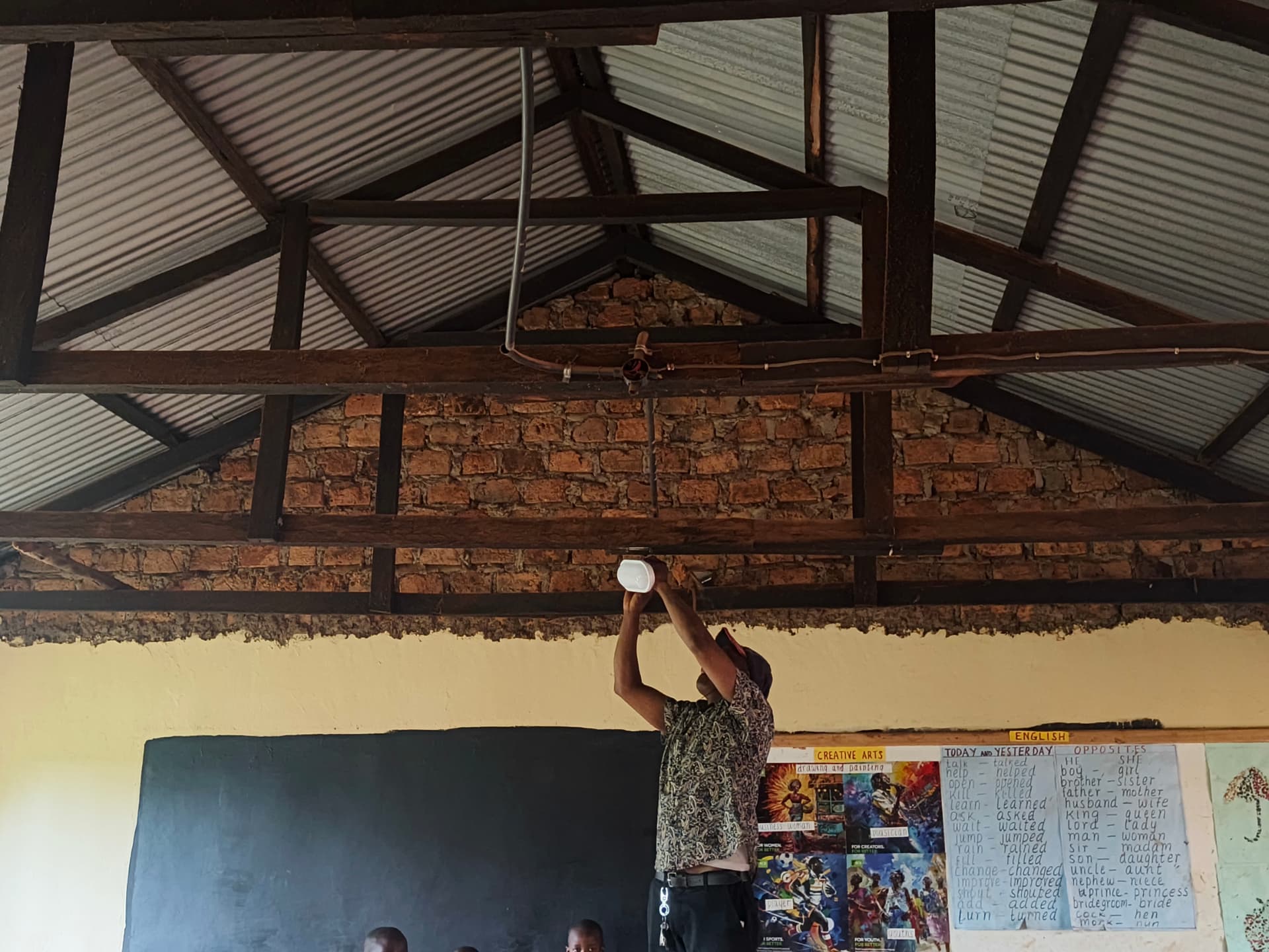 Worker installing a new ceiling light fitting in a classroom